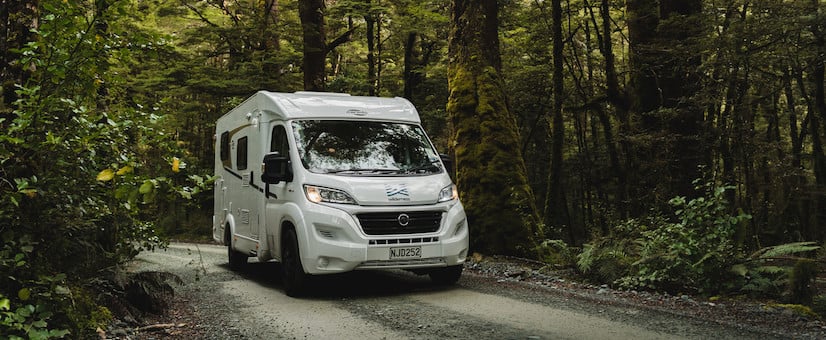 Motorhome crusing through a forest gravel road