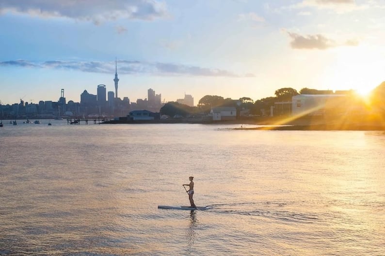 A paddler on the water in Auckland during a sunset