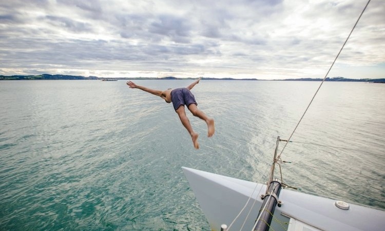 A person dives off a sailboat in the Bay of Islands, credit to Northland NZ