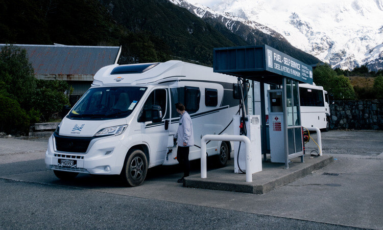 A woman filling up her motorhome with fuel at a petrol station in New Zealand