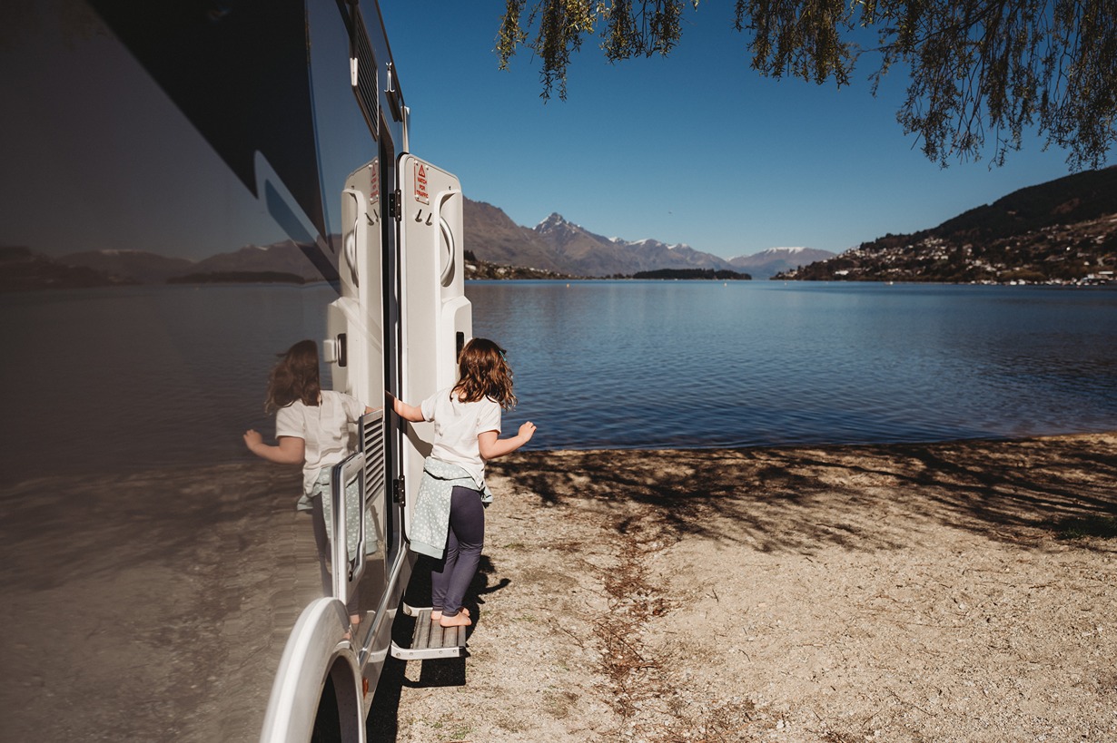 A kid getting out of a motorhome to view a lake