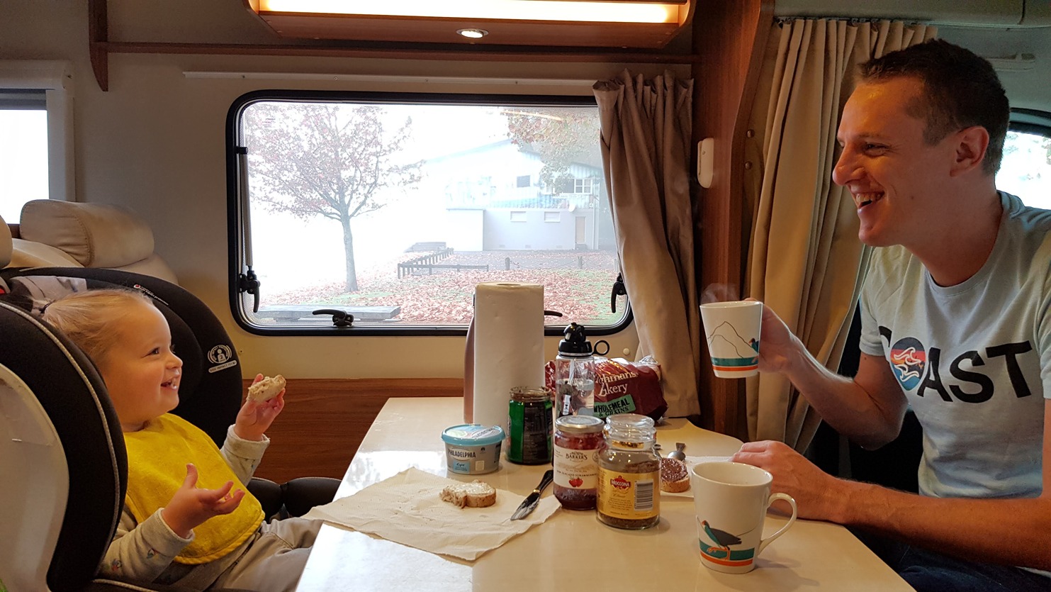 Dad and child having a breakfast in dining area of a motorhome