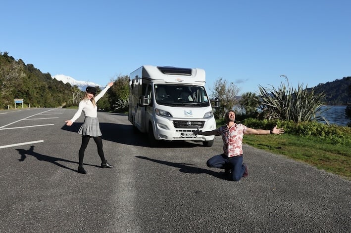 Couple on the road with a motorhome about to hug