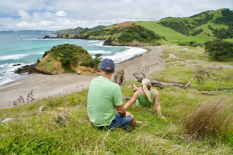 A couple sitting above a beach with a view