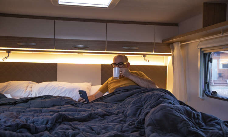 A man resting on a king bed in a Wilderness motorhome