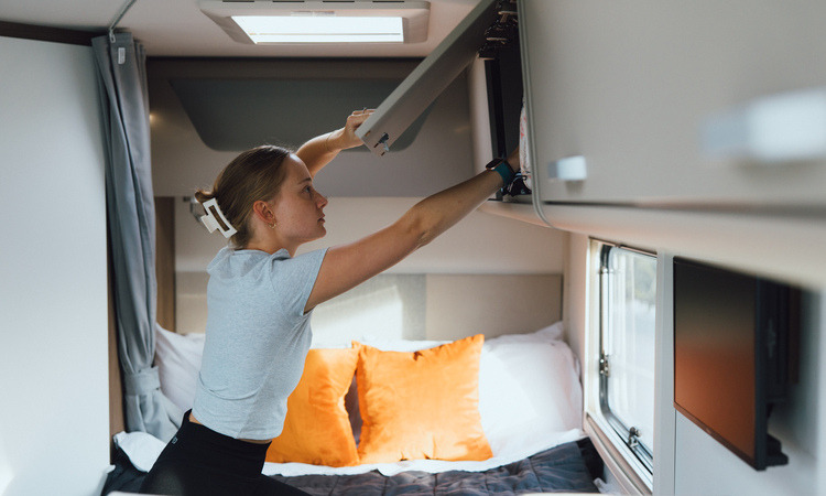 A woman using the storage space in a motorhome