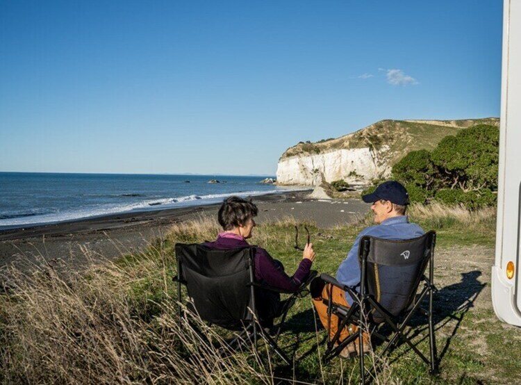 Couple sitting on camping chairs by beach
