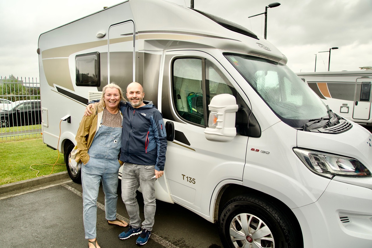 A couple posing in front of their motorhome after pickup