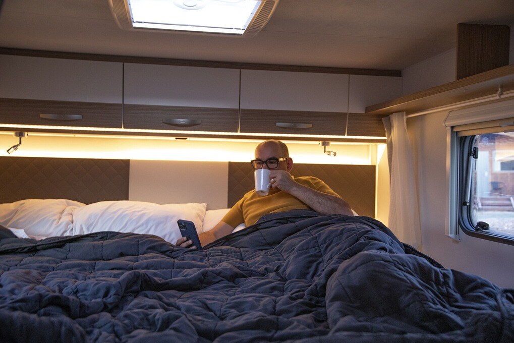 A man relaxing on the King/Twin for 4 Wilderness Motorhome King bed layout