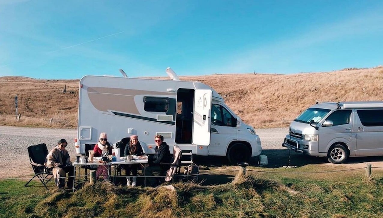 Group of travellers with their motorhome and outdoor table and chairs